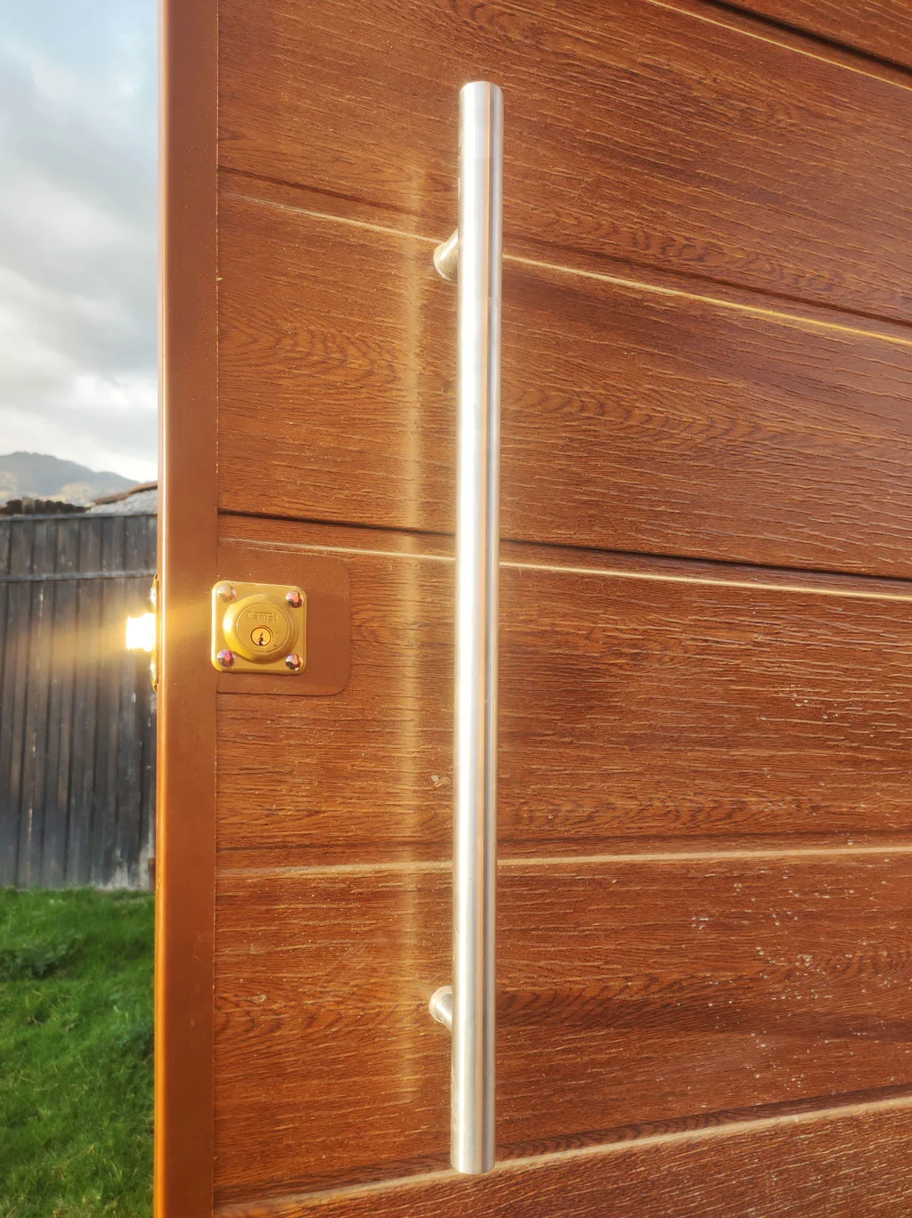 Puerta madera principal con manillon acero instalada en residencia.