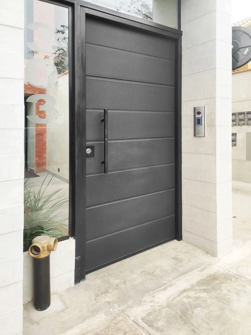 Puerta principal minimalista color grafito instalada en residencia.